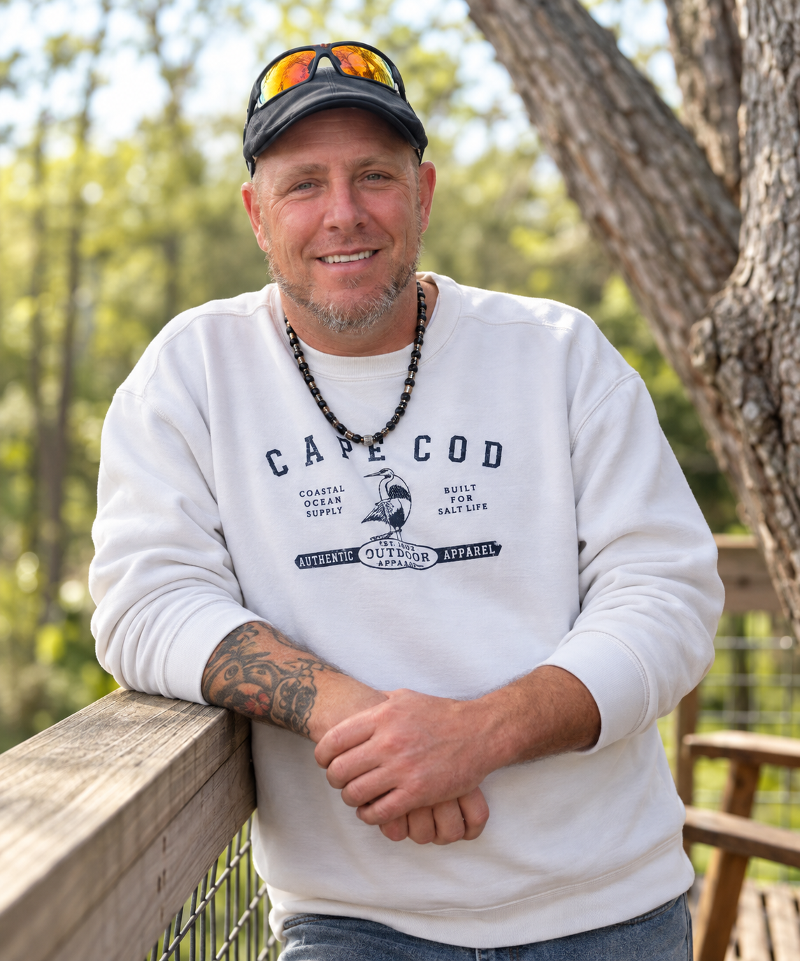 Ron Devine smiling outdoors, wearing a cap and a white sweatshirt